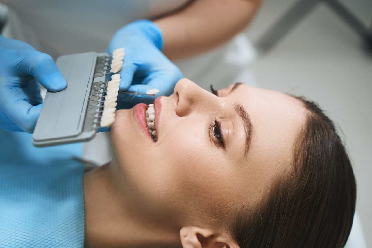dentist choosing the ideal dental veneers shade for a woman on a dental chair