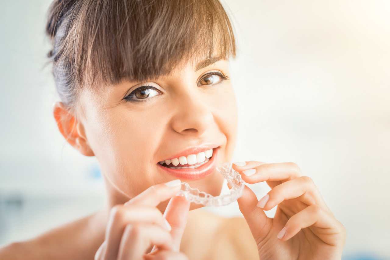 woman holding Invisible braces aligner towards her mouth